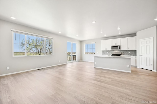 1957 S Coolidge Way, Aurora, CO 80018 - unfurnished living room featuring a sink, light wood finished floors, recessed lighting, and baseboards