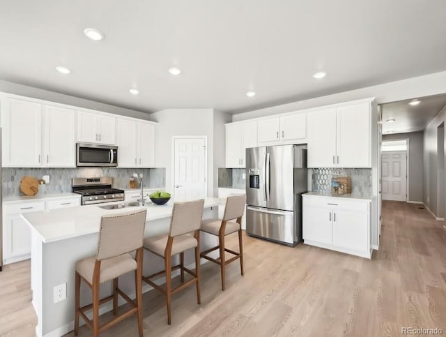 1957 S Coolidge Way, Aurora, CO 80018 - kitchen with appliances with stainless steel finishes, light wood finished floors, backsplash, and recessed lighting