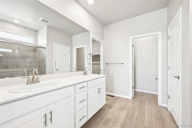 1957 S Coolidge Way, Aurora, CO 80018 - full bathroom featuring double vanity, wood finished floors, a tile shower, baseboards, and recessed lighting