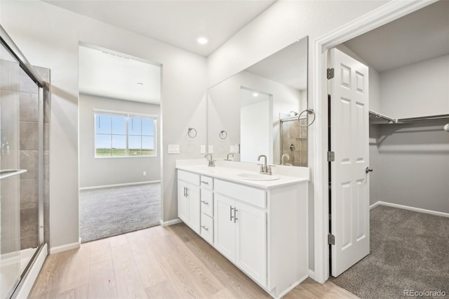 1957 S Coolidge Way, Aurora, CO 80018 - bathroom with double vanity, tiled shower, a walk in closet, baseboards, and recessed lighting
