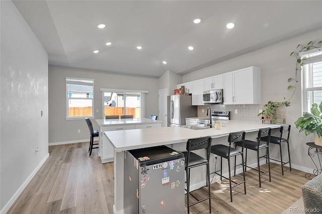 503 Bobcat Ct, Wiggins, CO 80654 - kitchen featuring stainless steel appliances, a peninsula, a kitchen bar, decorative backsplash, and a sink