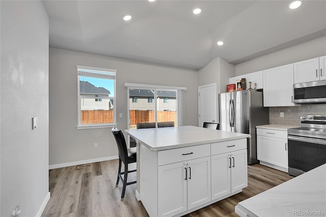 503 Bobcat Ct, Wiggins, CO 80654 - kitchen featuring appliances with stainless steel finishes, white cabinets, tasteful backsplash, light countertops, and wood finished floors