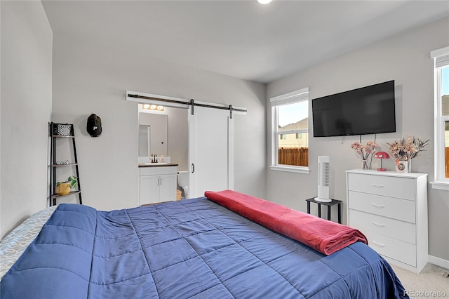 503 Bobcat Ct, Wiggins, CO 80654 - bedroom with a barn door, light carpet, and ensuite bathroom