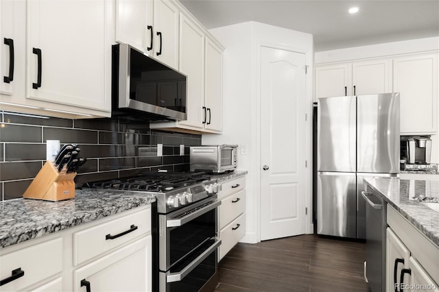 kitchen featuring light stone counters, stainless steel appliances, decorative backsplash, and white cabinets