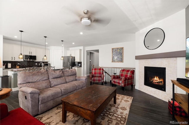 living room featuring a tiled fireplace and ceiling fan