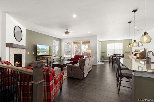 living room with dark wood-type flooring, ceiling fan, and sink