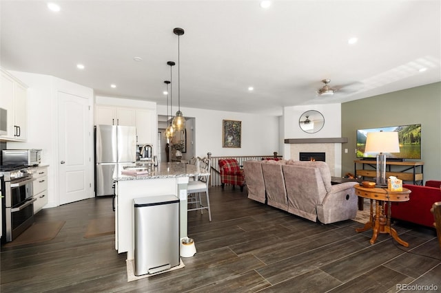 kitchen featuring appliances with stainless steel finishes, a breakfast bar, pendant lighting, white cabinetry, and a center island with sink