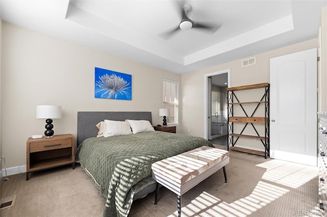 carpeted bedroom with ceiling fan and a raised ceiling