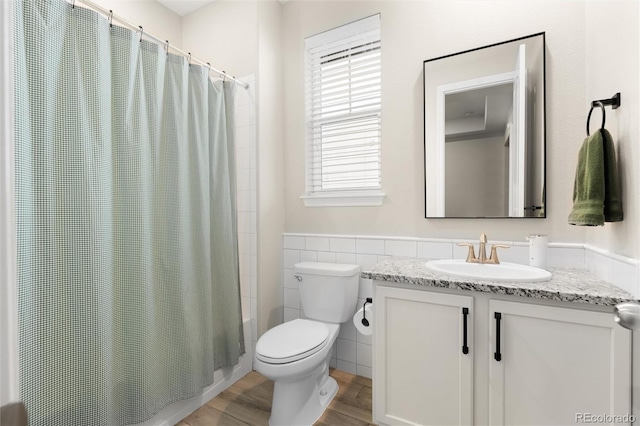 bathroom with hardwood / wood-style flooring, vanity, tile walls, and toilet