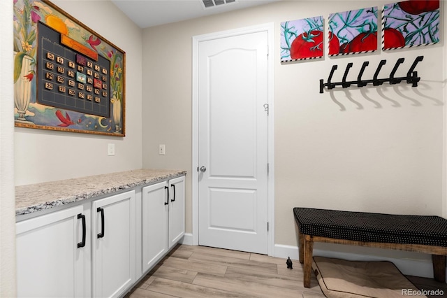 interior space featuring light stone counters, white cabinets, and light wood-type flooring