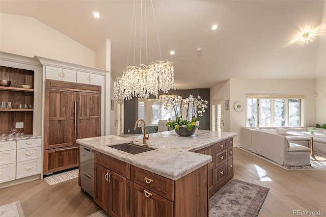 kitchen featuring a center island with sink, white cabinets, hanging light fixtures, paneled built in refrigerator, and a sink