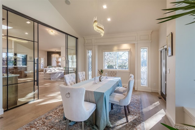 dining area featuring an inviting chandelier, light wood-style flooring, and vaulted ceiling