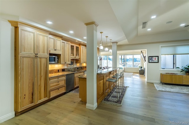 kitchen with a breakfast bar, pendant lighting, stainless steel appliances, visible vents, and glass insert cabinets