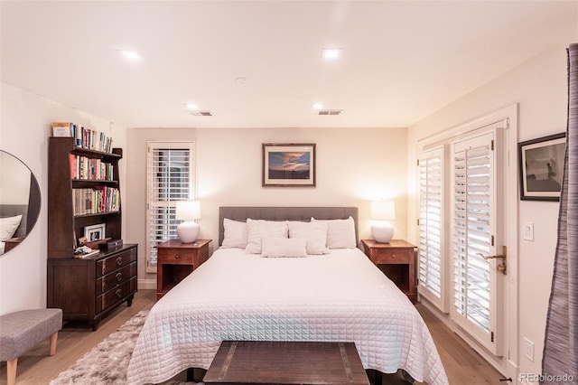 bedroom featuring light wood finished floors, access to outside, and visible vents