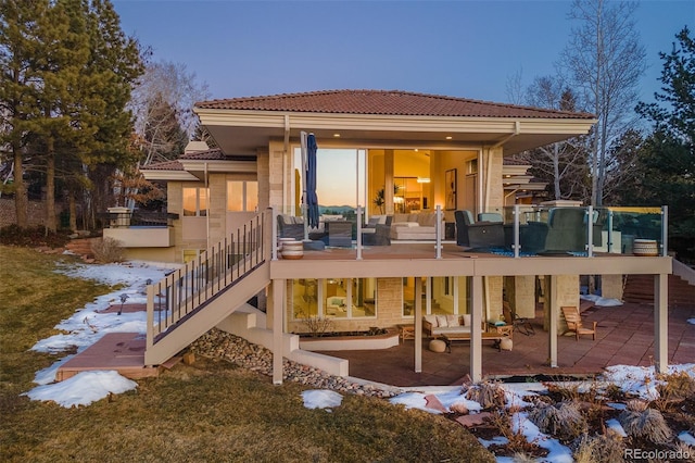 snow covered house featuring a tile roof, a patio, an outdoor hangout area, and stairs