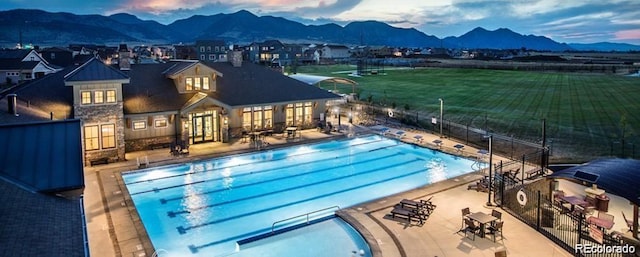 pool at dusk with a mountain view and a patio area