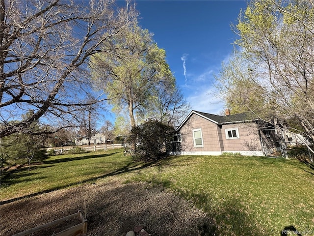 view of side of property with a yard, fence, and a chimney