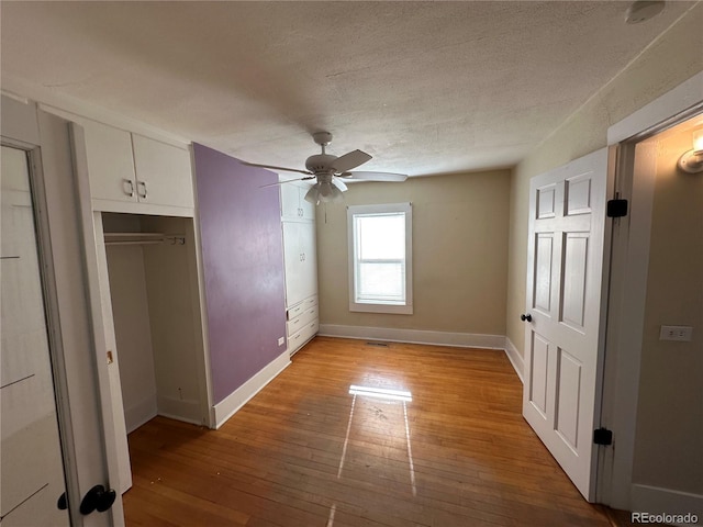 unfurnished bedroom with a textured ceiling, ceiling fan, wood-type flooring, and baseboards