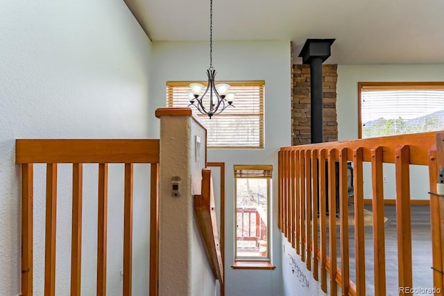 stairway featuring a healthy amount of sunlight, a wood stove, and an inviting chandelier