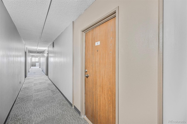 corridor with carpet flooring and a textured ceiling