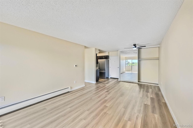 unfurnished living room with a baseboard heating unit, light wood-type flooring, a textured ceiling, a ceiling fan, and baseboards