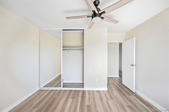 unfurnished bedroom with wood finished floors, a closet, a textured ceiling, and baseboards
