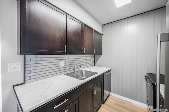 kitchen with a sink, light wood-style flooring, stainless steel dishwasher, dark brown cabinetry, and decorative backsplash