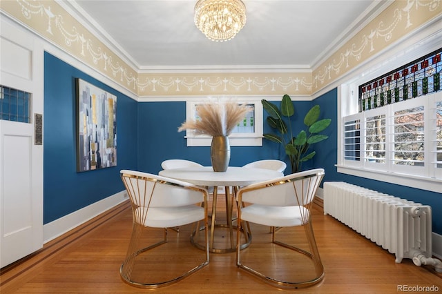 dining area with wood-type flooring, radiator, a notable chandelier, and ornamental molding