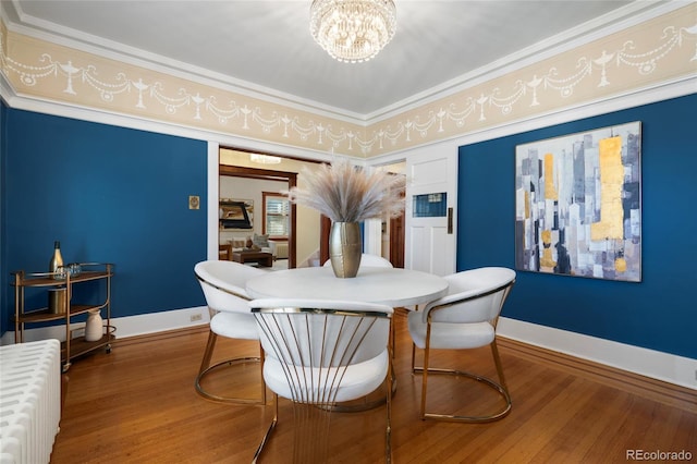 dining area featuring a notable chandelier, hardwood / wood-style floors, and radiator