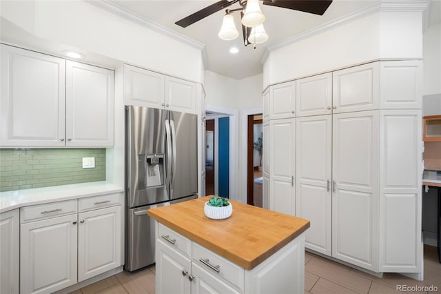 kitchen with stainless steel fridge with ice dispenser, decorative backsplash, white cabinets, and a kitchen island