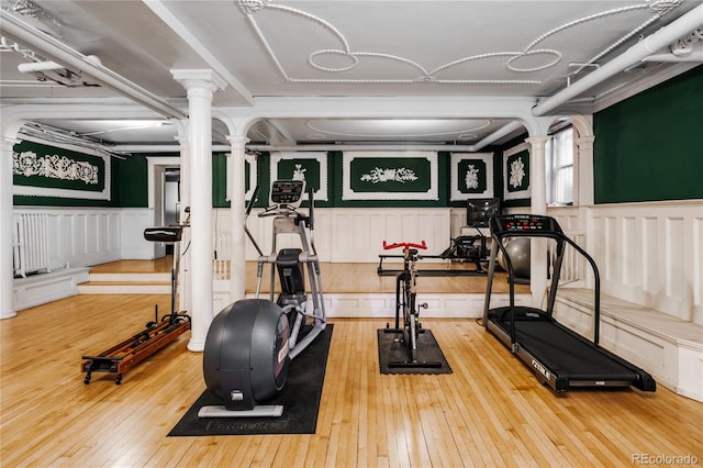 workout area featuring decorative columns and light hardwood / wood-style flooring