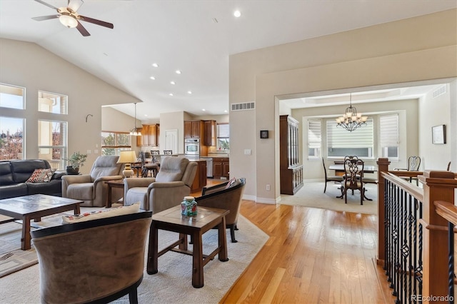 8714 E 148th Cir, Thornton, CO 80602 - living area featuring baseboards, light wood-style floors, visible vents, lofted ceiling, and ceiling fan with notable chandelier