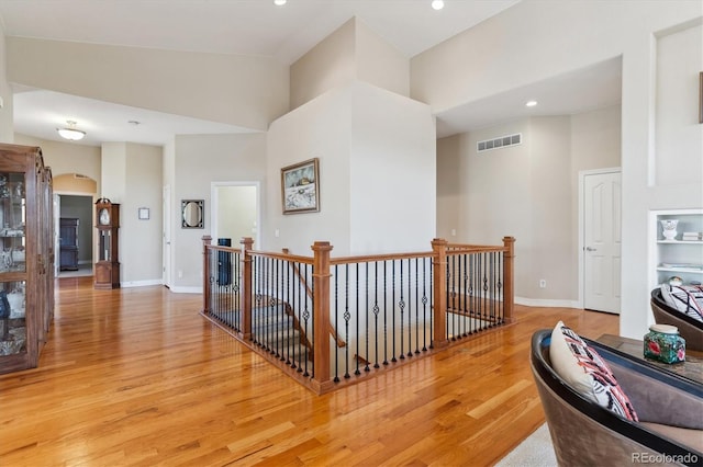 8714 E 148th Cir, Thornton, CO 80602 - hallway featuring light wood-type flooring, visible vents, a towering ceiling, and an upstairs landing