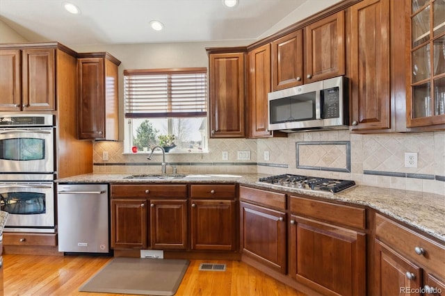 8714 E 148th Cir, Thornton, CO 80602 - kitchen with visible vents, a sink, appliances with stainless steel finishes, light wood-style flooring, and decorative backsplash