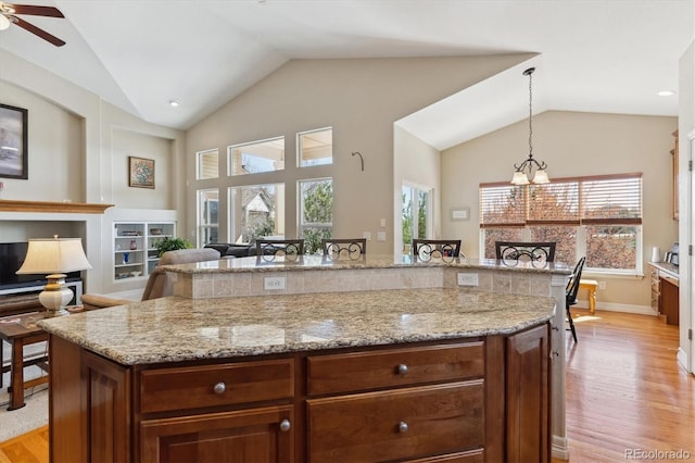 8714 E 148th Cir, Thornton, CO 80602 - kitchen featuring a wealth of natural light, light stone countertops, light wood-type flooring, and lofted ceiling