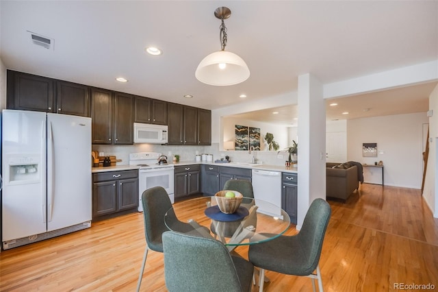 kitchen featuring sink, decorative light fixtures, white appliances, tasteful backsplash, and light hardwood / wood-style flooring