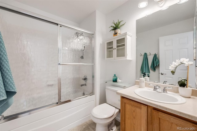 full bathroom with tile patterned flooring, shower / bath combination with glass door, vanity, and toilet