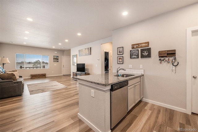 kitchen featuring sink, light hardwood / wood-style flooring, light stone counters, stainless steel dishwasher, and kitchen peninsula