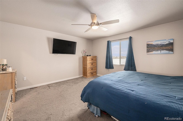 carpeted bedroom featuring ceiling fan and a textured ceiling