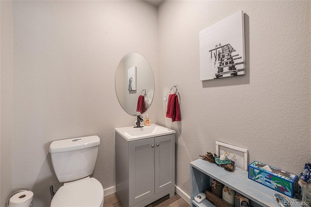 bathroom with vanity, toilet, and hardwood / wood-style floors