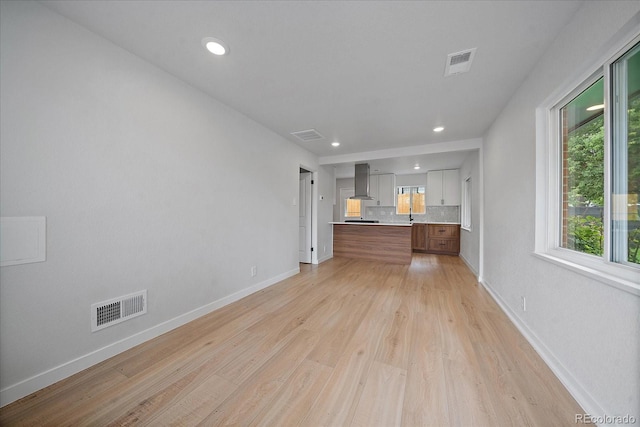 unfurnished living room featuring sink and light hardwood / wood-style flooring