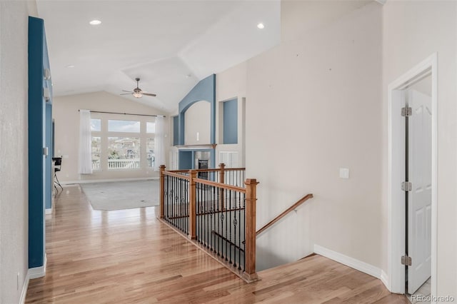 corridor featuring baseboards, vaulted ceiling, an upstairs landing, light wood-style floors, and recessed lighting