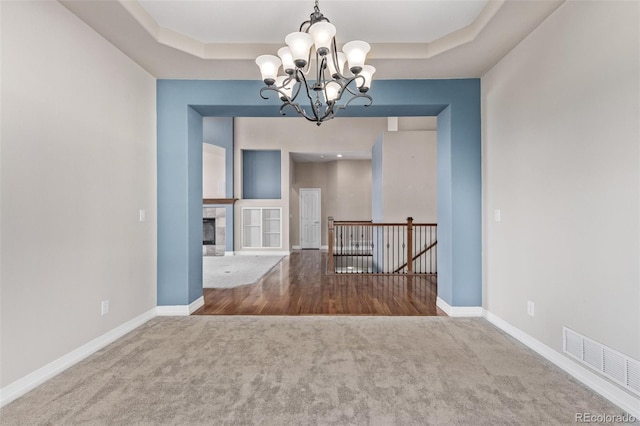 empty room with visible vents, a tray ceiling, and baseboards