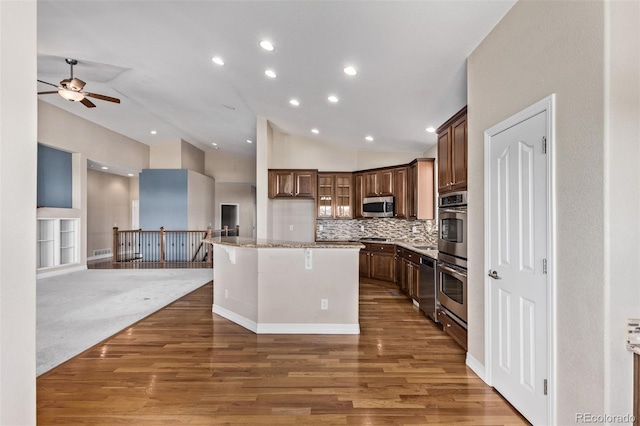 kitchen featuring lofted ceiling, stainless steel appliances, a kitchen breakfast bar, open floor plan, and a center island