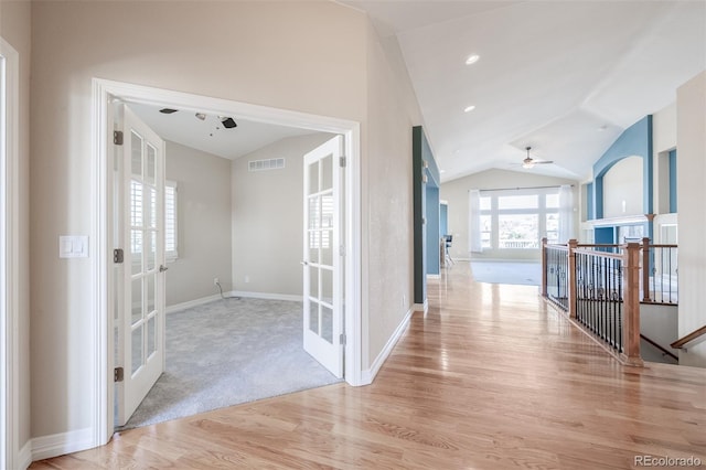 hall with french doors, light wood finished floors, visible vents, vaulted ceiling, and baseboards