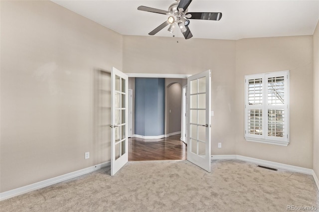 spare room with french doors, light colored carpet, and baseboards