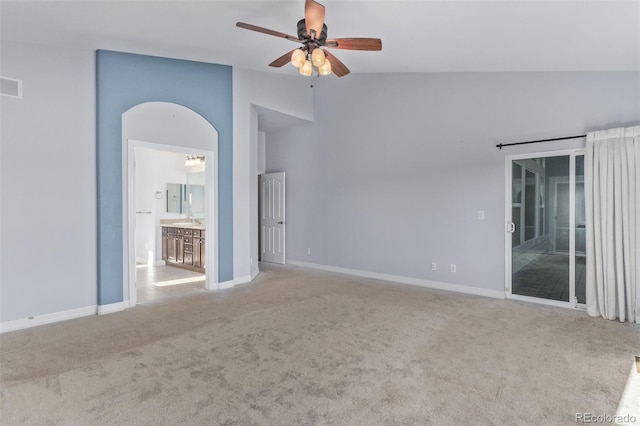 empty room with ceiling fan, light colored carpet, visible vents, baseboards, and vaulted ceiling