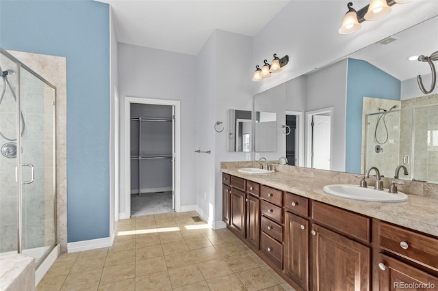 full bath featuring a stall shower, a walk in closet, a sink, and double vanity