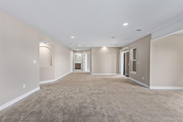 spare room featuring visible vents, light colored carpet, and baseboards