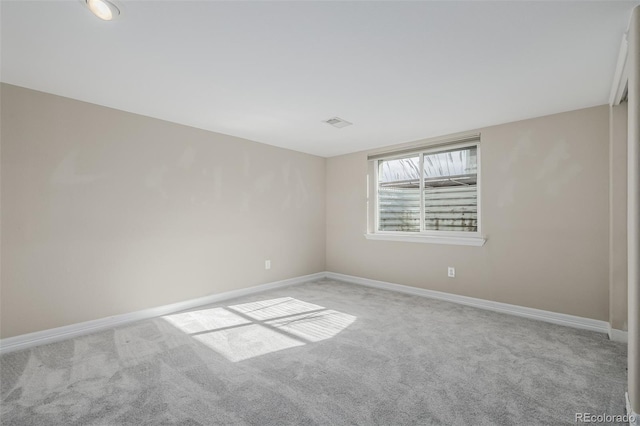 spare room featuring light carpet, visible vents, and baseboards